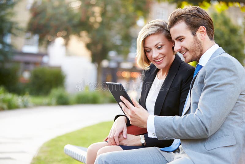 business couple using digital tablet park bench looking screen smiling 40096970